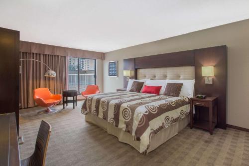 a hotel room with a large bed and a desk at Ramada by Wyndham Kelowna Hotel & Conference Center in Kelowna