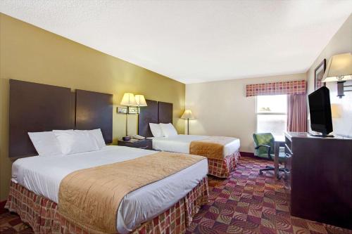 a hotel room with two beds and a flat screen tv at Days Inn & Suites by Wyndham Ridgeland in Ridgeland