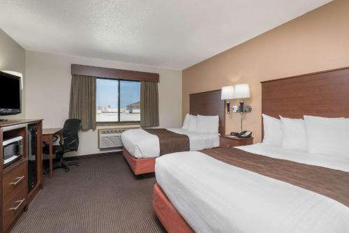 ビズマークにあるAmericInn by Wyndham Bismarckのベッド2台、薄型テレビが備わるホテルルームです。