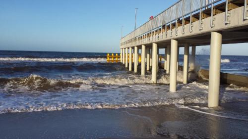 a pier over the ocean with waves at Rajska Mierzeja , SAUNA , JAKUZZI ,BASEN Z PODGRZEWANĄ WODĄ , KLIMATYZACJA-OGRZEWANIE , PLAC ZABAW , ROWERY , TARAS in Sarbinowo