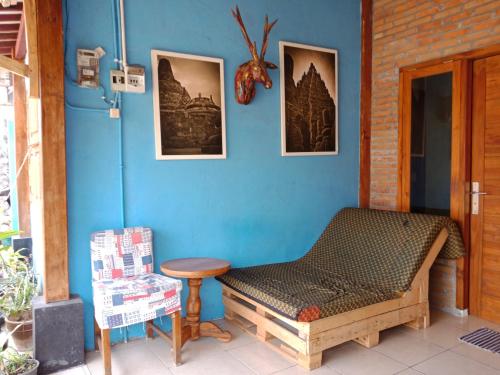 a blue room with a bench and pictures on the wall at Arjuna Garden Homestay in Yogyakarta