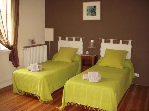 two beds in a bedroom with green sheets at La Maison des Aurélines in Puisseguin