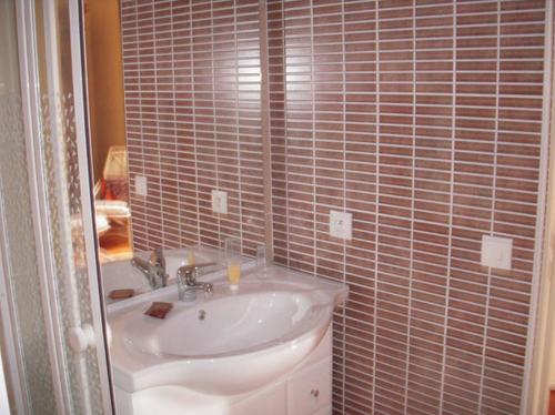 a bathroom with a sink and a tiled wall at La Maison des Aurélines in Puisseguin