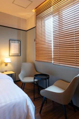 a bedroom with two chairs and a bed and a window at Brown-Dot Hotel Shinho in Busan