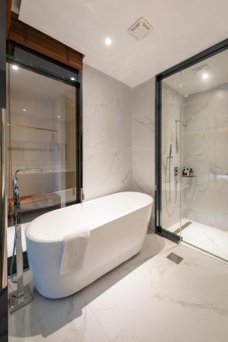 a white bath tub in a bathroom with a shower at Brown-Dot Hotel Shinho in Busan