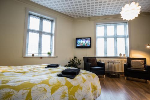 a bedroom with a bed and two chairs and a tv at Bed & Breakfast Holstebro in Holstebro