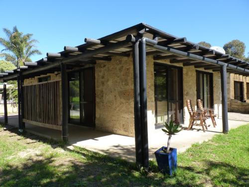 a house with a pergola and a plant in front of it at Happy Dogs Cottage Margaret River in Margaret River Town
