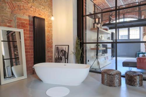 ein Badezimmer mit einer großen weißen Badewanne und einer Ziegelwand in der Unterkunft The Loft Unique Designed in Florenz