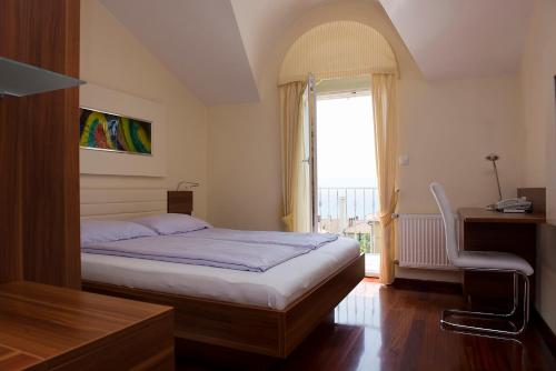 a bedroom with a bed and a desk and a window at Pansion Maestral in Novi Vinodolski