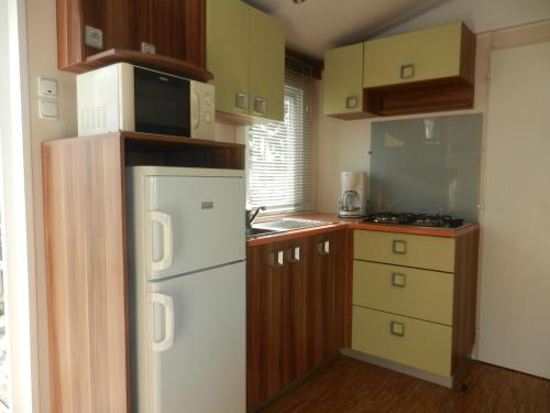 una pequeña cocina con nevera blanca y armarios en Mareva37, en Trogues