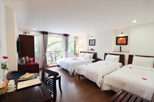 a hotel room with three beds and a table and a desk at Hanoi Siva Luxury Hotel & Travel in Hanoi