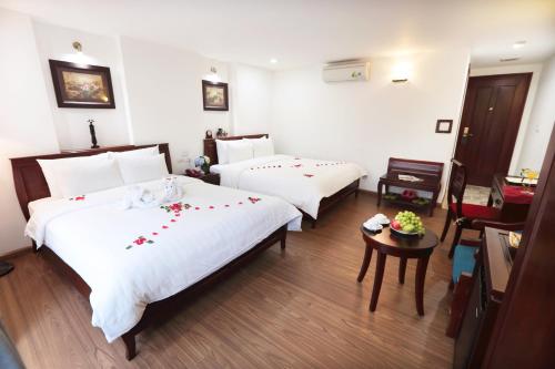 a hotel room with two beds and a table at Hanoi Siva Luxury Hotel & Travel in Hanoi