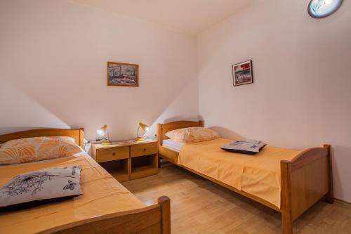 a bedroom with two beds and a clock on the wall at Apartments Dabović in Cres