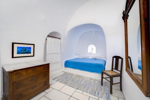 a bedroom with a blue bed and a wooden dresser at Chelidonia Traditional Villas in Oia