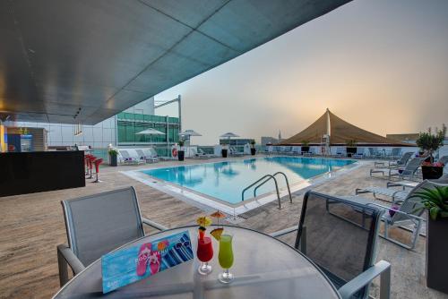 una piscina con tavolo e sedie e un negozio di articoli per la vendita di asterisco. di J5 Hotels – Port Saeed a Dubai