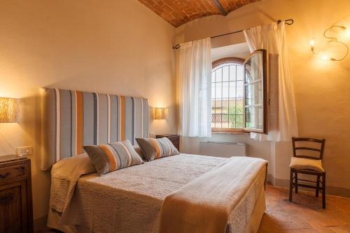 a bedroom with a bed and a window and a chair at Villa Aia Vecchia in Bibbona