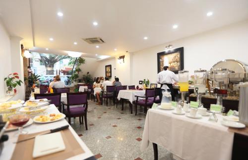 a restaurant with people sitting at tables and a chef preparing food at Hanoi Siva Luxury Hotel & Travel in Hanoi
