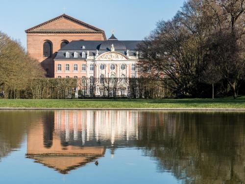 a large building with a reflection in a body of water at Hotel Haus am Berg in Trier
