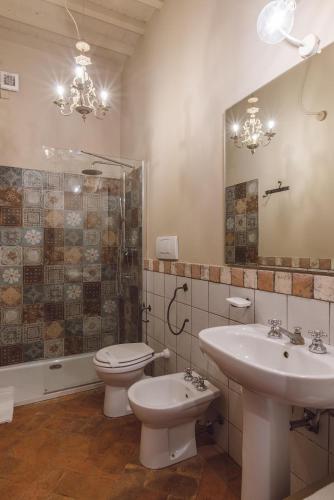 a bathroom with a sink and a toilet and a mirror at Villa Aia Vecchia in Bibbona