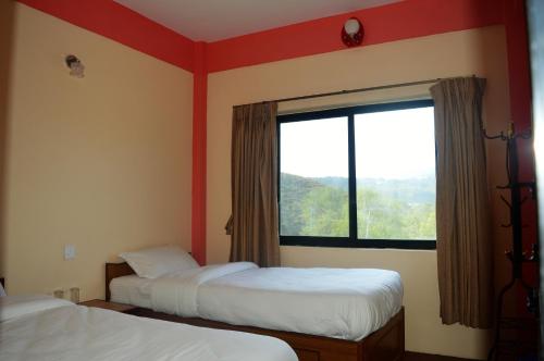 two beds in a room with a large window at Panorama Guest House in Nagarkot