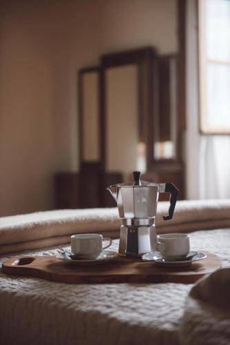 a coffee maker and two cups on a bed at Villa Aia Vecchia in Bibbona