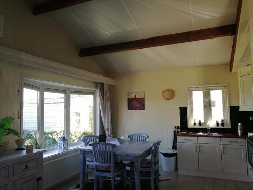 a kitchen with a table and chairs and a window at Chalet Stalland in Sint Annaland