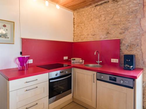 - une cuisine rouge avec évier et cuisinière dans l'établissement Cozy Cottage in Aquitaine with Private Swimming Pool, à Peyzac-le-Moustier