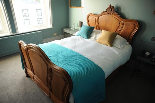 a bedroom with a large bed with a wooden headboard at The Tunbridge Wells Hotel in Royal Tunbridge Wells