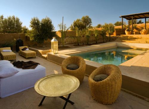 a patio with a table and chairs and a pool at The Capaldi Hotel, Restaurant & Spa in Lalla Takerkoust