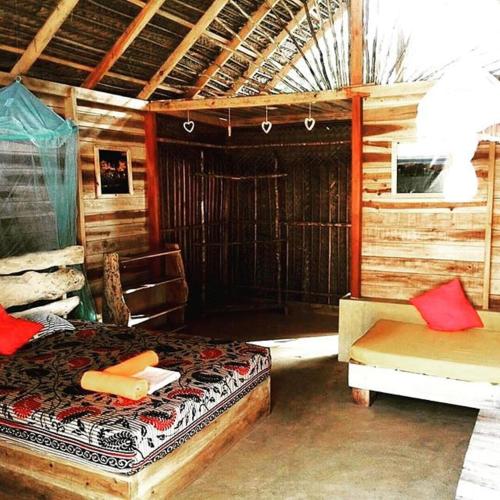 a bedroom with a bed and a bench in a cabin at Margarita Village kite school kalpitiya in Kalpitiya