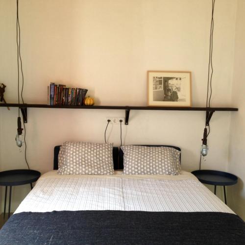 a bed with two pillows and a shelf above it at village loft in Cercal