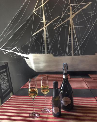two bottles of wine and two glasses on a table with a boat at Hotel Helada in Tivat