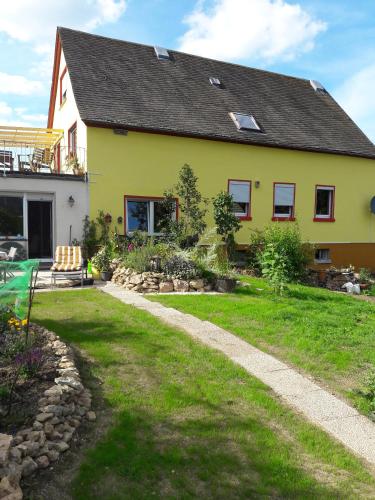 a yellow house with a garden and a lawn at Urlaub am Auberg in Gerolstein