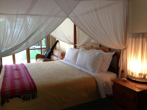 a bedroom with a large bed with white curtains at Villa Kunang in Seminyak