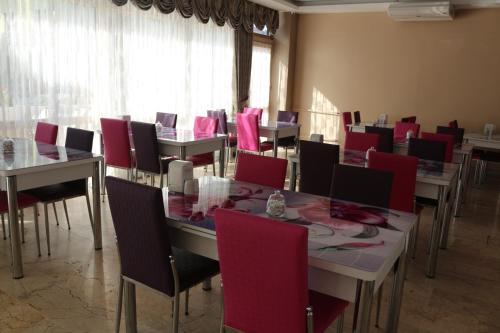 un comedor con mesas y sillas con sillas rojas en ECS Suw Hotel, en Atakum