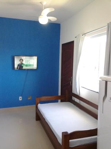 1 dormitorio con pared azul, cama y ventana en Caribe Brasileiro, en Arraial do Cabo