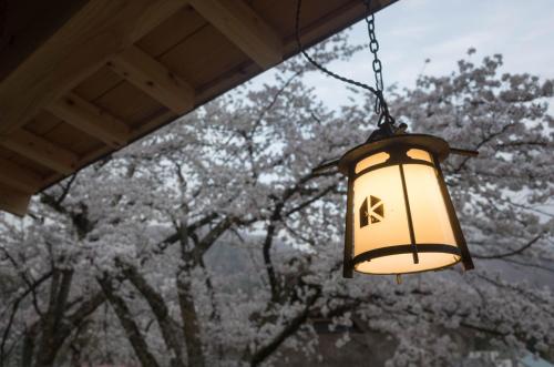 a light hanging from a porch with trees in the background at Shirakawago Guest House Kei in Shirakawa