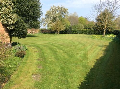 a large field of grass with trees and a house at White Hall Farm in Leamington Spa