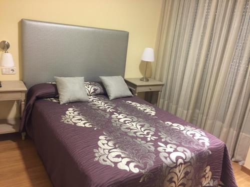 a bedroom with a bed with a purple comforter at Hostal Santa Baia in Ribadumia