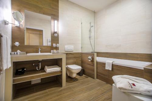a bathroom with a toilet, sink, and bathtub at Mamaison Hotel Andrassy Budapest in Budapest
