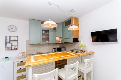 a kitchen with green cabinets and white chairs at Apartment Hello Love in Split