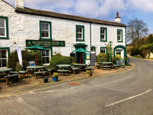 um edifício com mesas e bancos do lado da rua em The Racehorses Hotel em Kettlewell