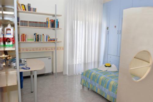 a bedroom with a bed and a table and a shelf with books at Mare And City House in Manfredonia