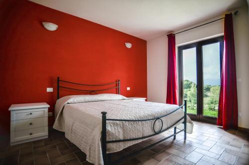 um quarto com uma cama e uma parede vermelha em Agriturismo Airone em Pitigliano