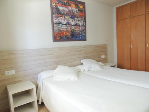 una camera con due letti e un dipinto sul muro di Apartamentos Turísticos Augustus a Cambrils
