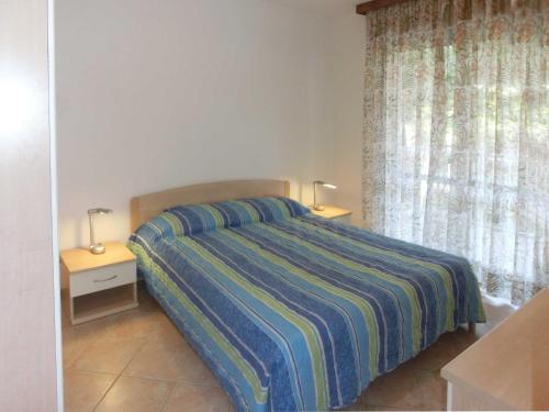 1 dormitorio con 1 cama con edredón de rayas y 2 mesas en La Duna, en Lignano Sabbiadoro