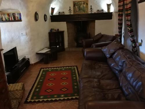 a living room with a leather couch and a fireplace at Cueva Peralta in Cortes de Baza