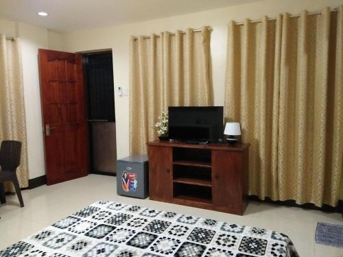 a bedroom with a bed and a television on a dresser at Lourdes Inn in Manila