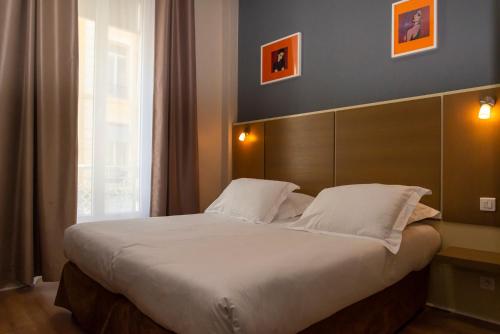 a bedroom with a large bed with white sheets and pillows at Hotel Amiraute in Cannes