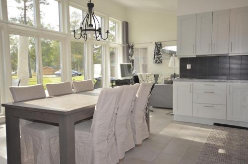 a dining room with a table and chairs and a kitchen at Sudersand Resort in Fårö